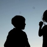 stock-footage-silhouettes-of-girl-blowing-up-soap-bubbles-and-boy-catching-them-against-sky
