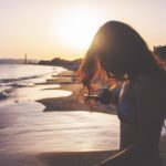 girl with phone on the beach