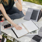 woman-with-planner-and-laptop-sitting-on-blanket-in-park-4497730