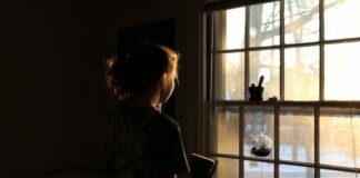 lonely woman standing by window