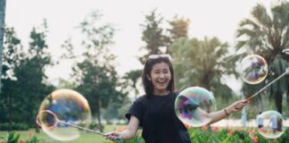 Not Just For Kids: How Embracing Play As An Adult Can Improve Your Mental Health Woman Laughing While Playing With Bubbles As Adult