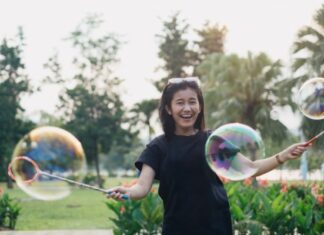 Woman Laughing While Playing With Bubbles As Adult