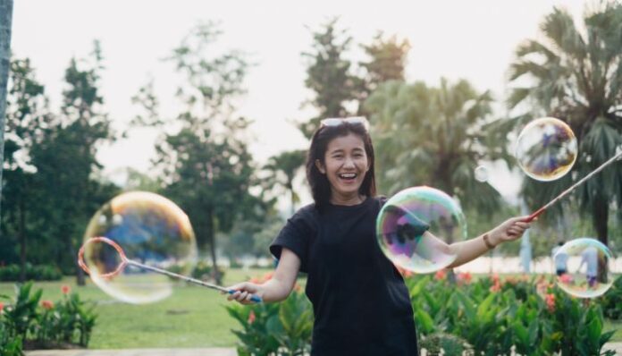 Woman Laughing While Playing With Bubbles As Adult