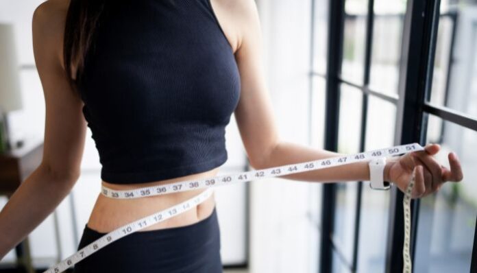 Woman With An Eating Disorder Measuring Weight Loss