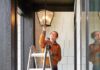 Woman Fixing Lamp Outside Home
