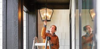 Woman Fixing Lamp Outside Home