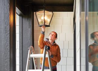 Woman Fixing Lamp Outside Home
