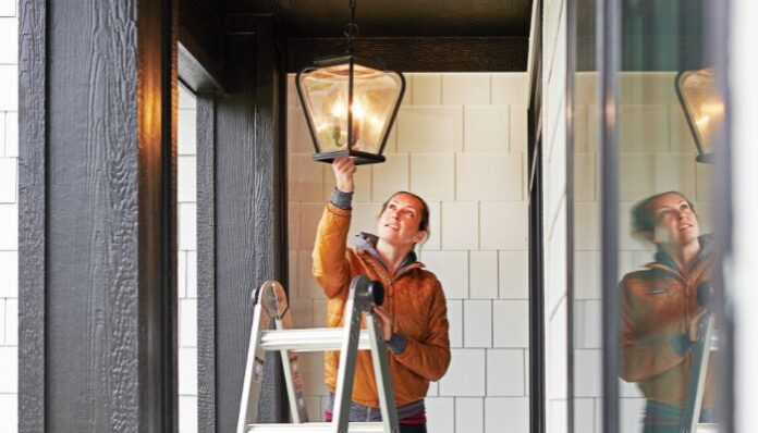 Woman Fixing Lamp Outside Home