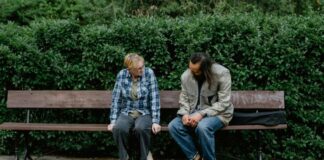 How Talking To Strangers Helped Me Feel Human Again Two People on a Bench Talking with Bushes in the Background