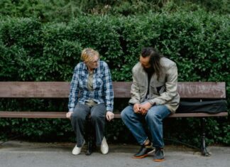 How Talking To Strangers Helped Me Feel Human Again Two People on a Bench Talking with Bushes in the Background