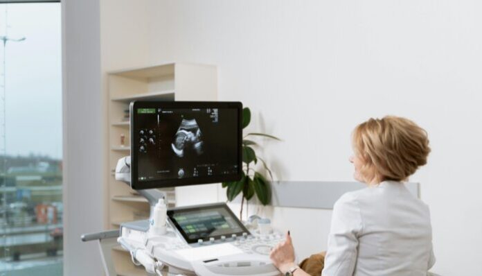 Woman performing ultrasound after patient noticed body signals of pregnancy