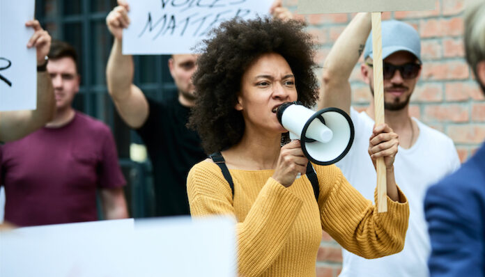 African American woman shouting through megaphone on anti-racism protest.