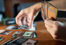 What Makes Some Magic Cards Worth Hundreds & Others Worth Nothing Person Playing Magic The Gathering at a Wooden Table