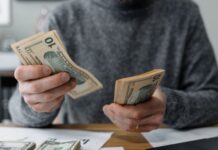 The Money Lesson No One Prepared Me For During Residency Young male medical student counting cash and determining his budget using calcuator and other tools