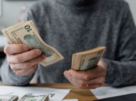 Young male medical student counting cash and determining his budget using calcuator and other tools