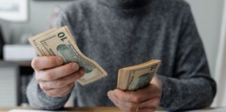 Young male medical student counting cash and determining his budget using calcuator and other tools