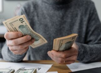 Young male medical student counting cash and determining his budget using calcuator and other tools