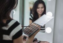 Woman putting on eyeshadow in mirror using eye shadow palette