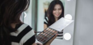 Woman putting on eyeshadow in mirror using eye shadow palette