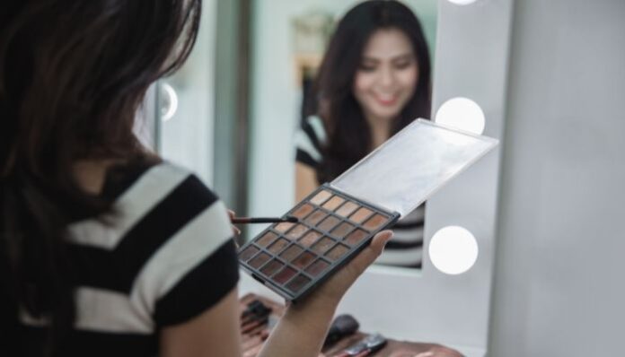 Eyeshadow Palette Woman putting on eyeshadow in mirror using eye shadow palette