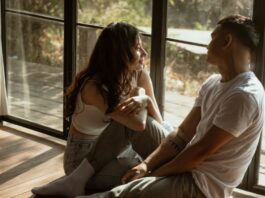 Couple sitting near a window in their home, talking about their personal bedroom kinks