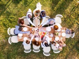 Wedding Party gathered around a wooden table at a backyard wedding reception, celebrating with a toast.