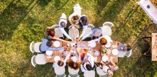 Wedding Party gathered around a wooden table at a backyard wedding reception, celebrating with a toast.